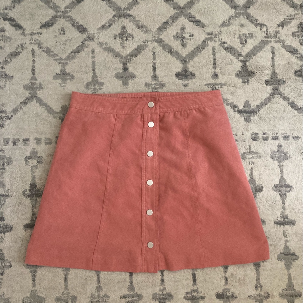 Pink mini skirt with snap buttons on front.
